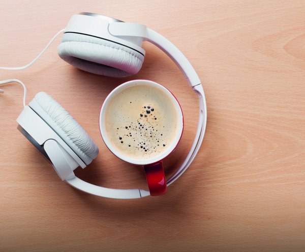 Eine Tasse Kaffee mit Kopfhörern als Symbolbild für Freizeit und Ruhe.